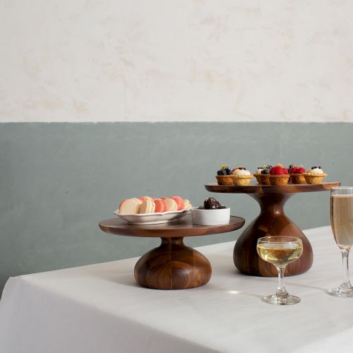 A pastry dessert table with two tier stands of macarons and fruit, plus glasses of champagne on a white table.
